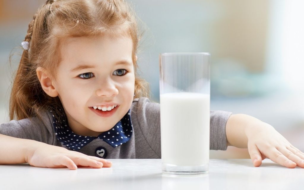 Little girl stares down a glass of milk.