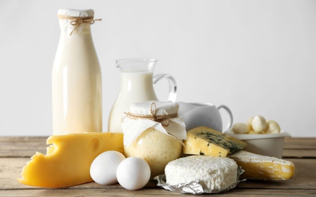 Assorted dairy products such as cheese and milk sit on a table.