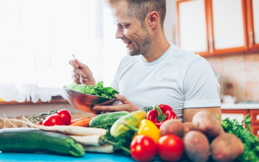 Man is making a salad with all sorts of vegetables.