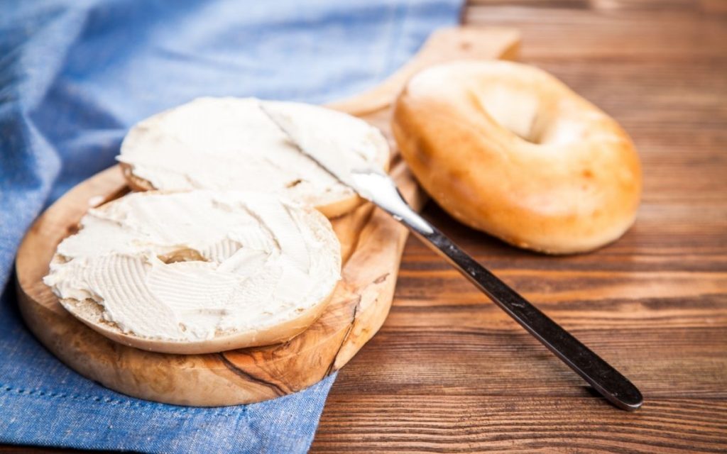 Cream cheese being spread on a bagel.