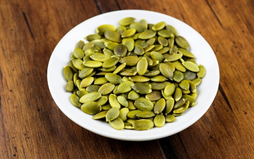 A bowl of pumpkin seeds on a table.
