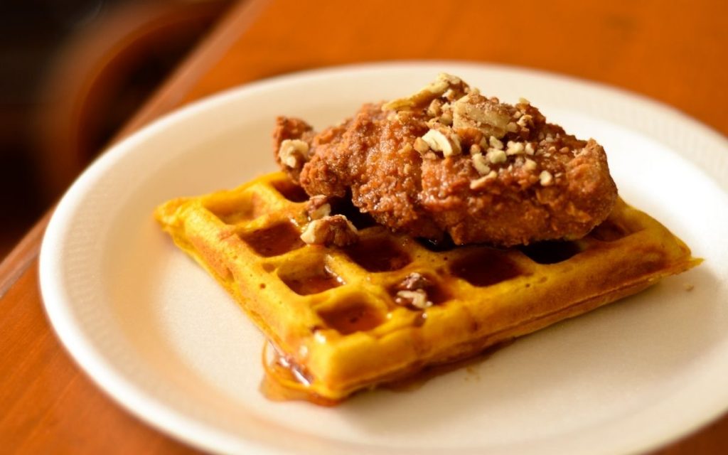 Chicken & waffles sit on a plate.