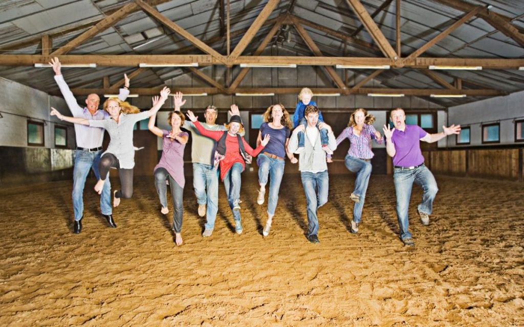 A happy family of farmers dance together in a barn.