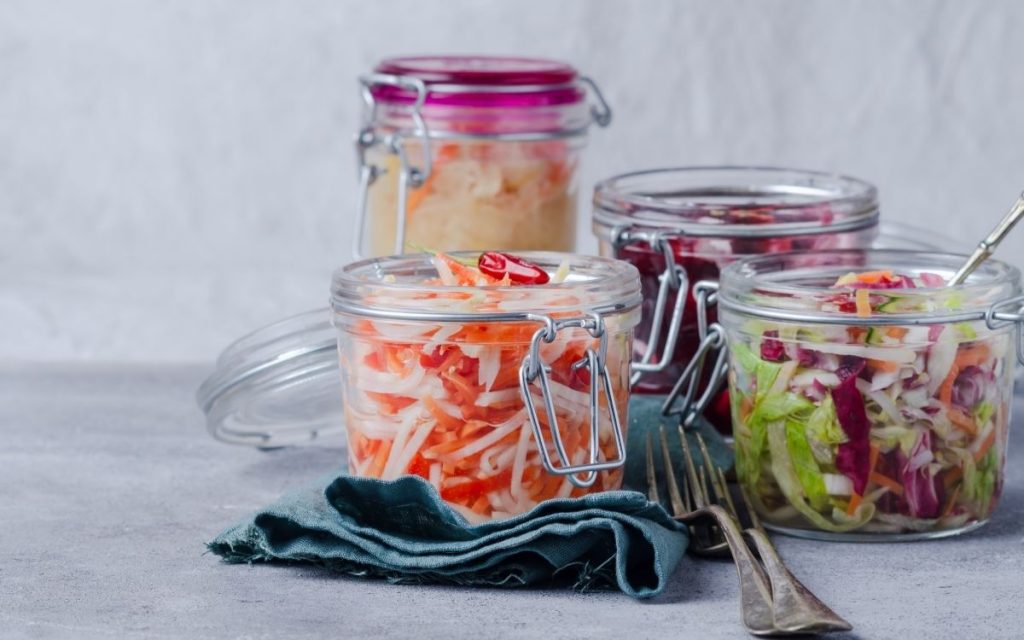 Different fermented foods on a table in pickling jars.