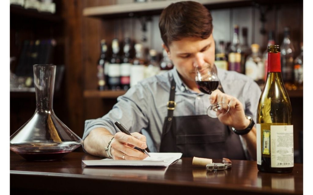 Man sniffs wine whilst taking notes. 