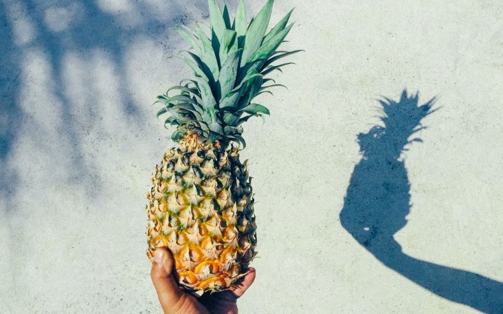 Holding a pineapple up with a reflection shadow.