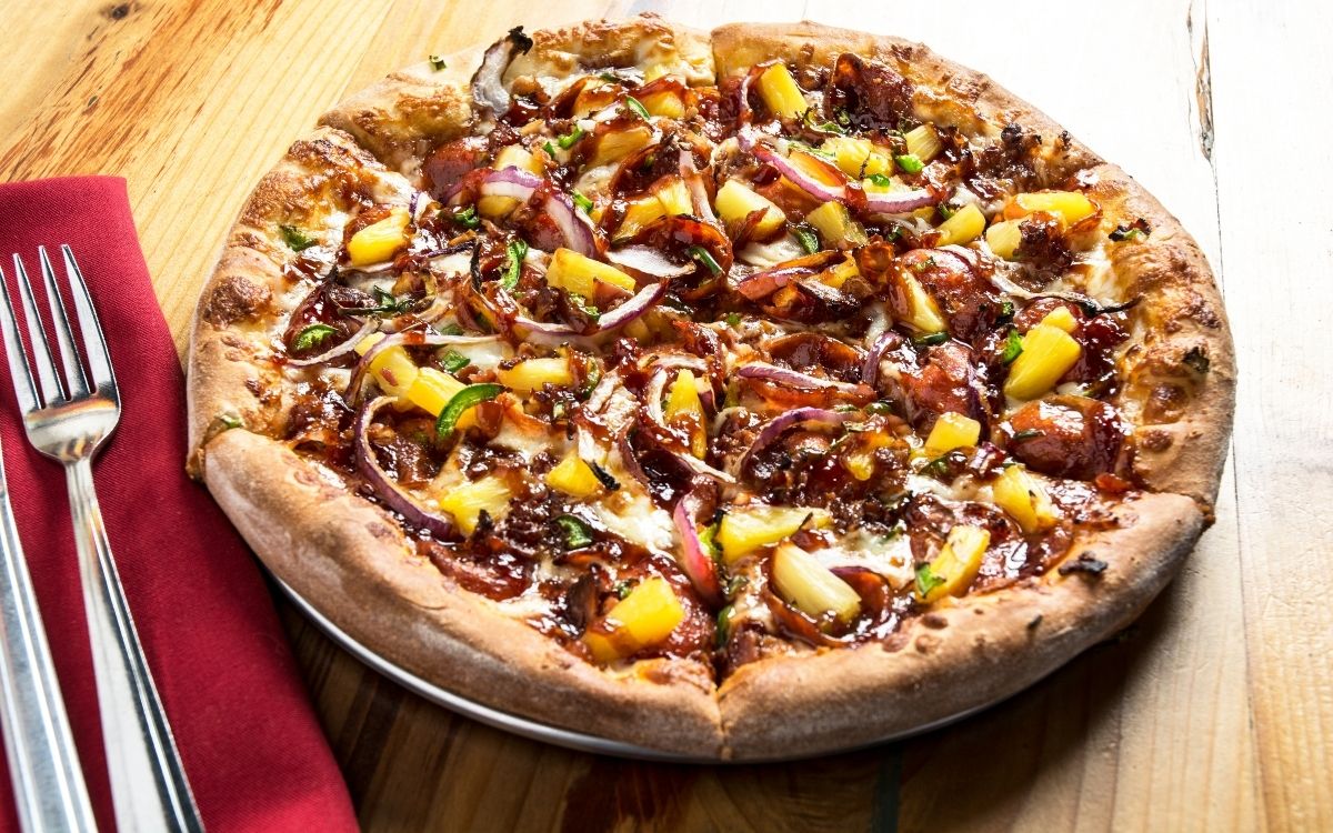 A pineapple topped pizza ready to eat.