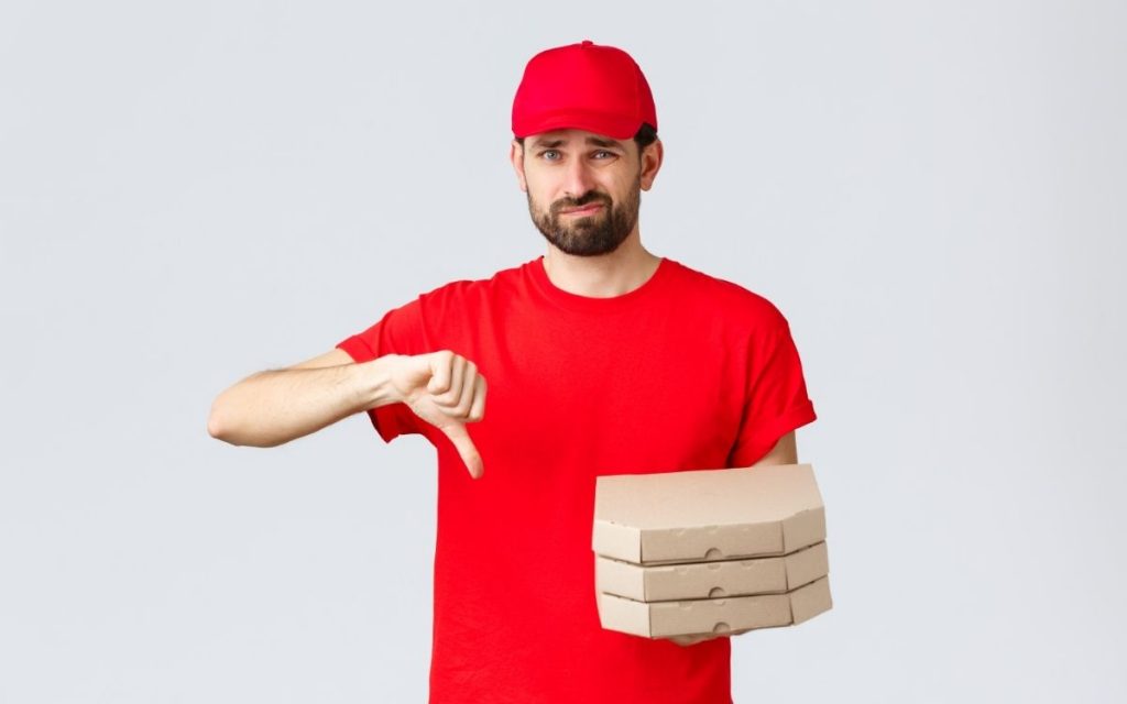 Man with pizza boxes looks unhappy and holds his thumb down.