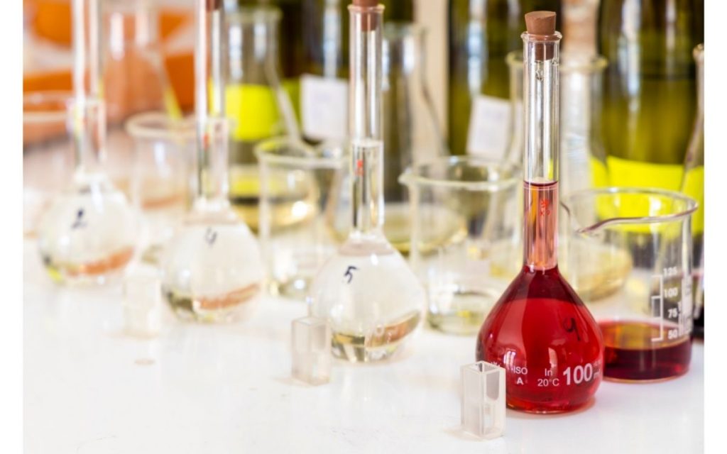 Science beakers of wine sit in a laboratory. 