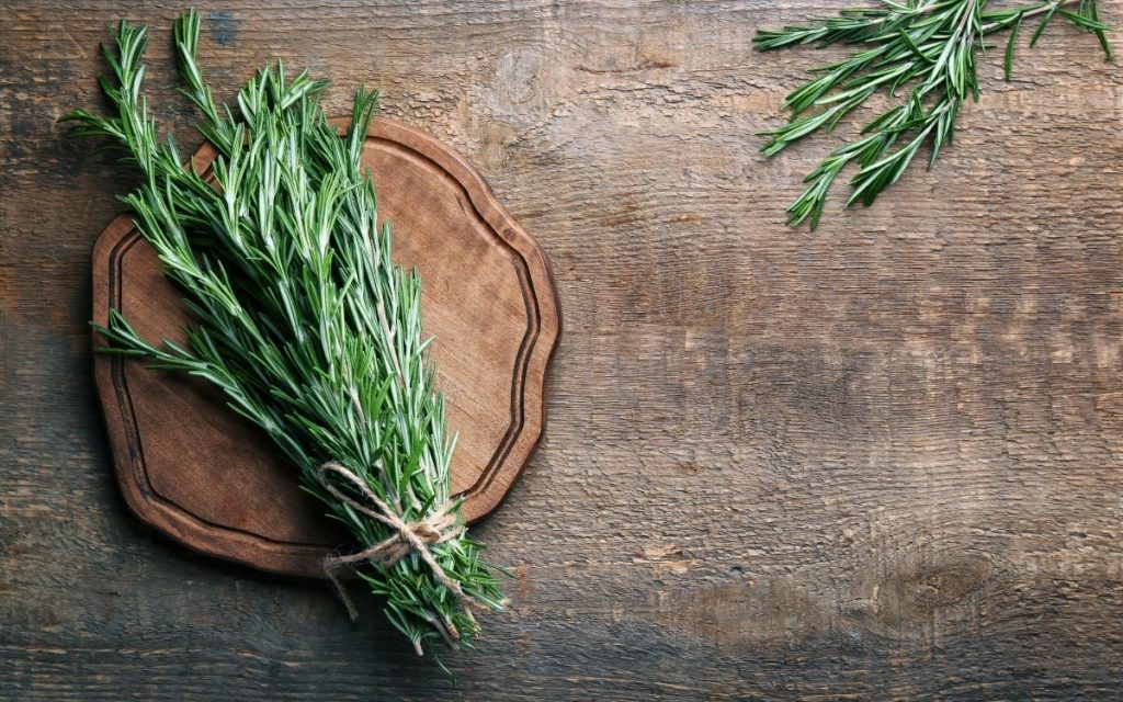 A bunch of rosemary on a wooden board.